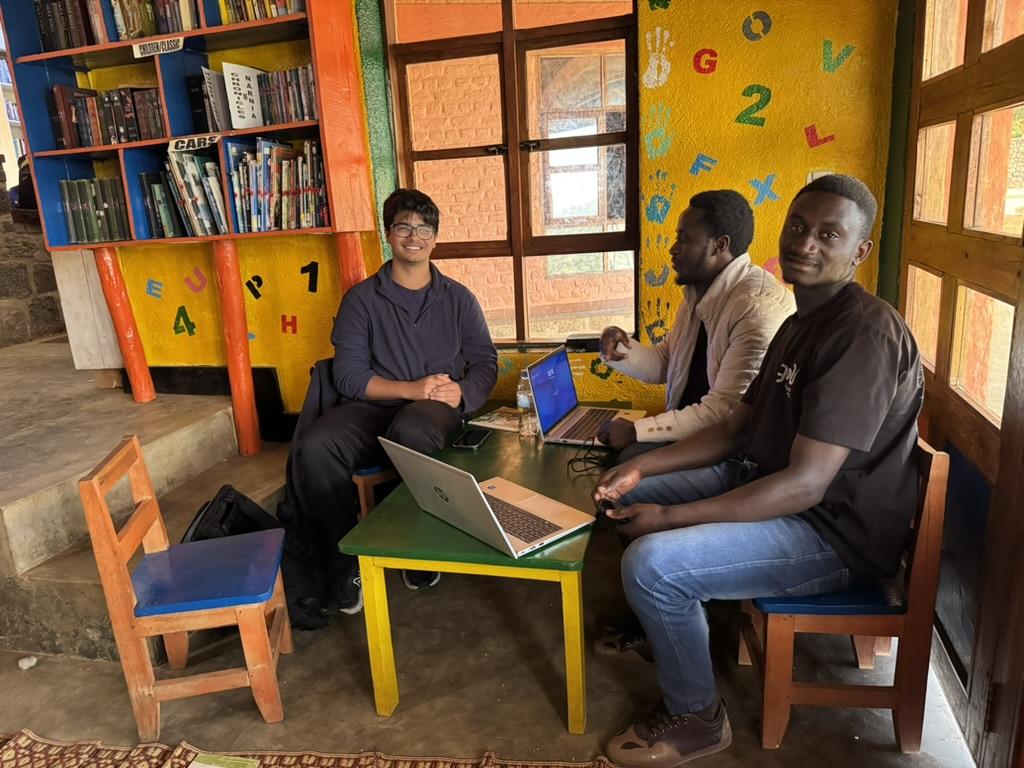 Students and peer educators collaborating around a laptop during a 2025 gold-youth program session.
